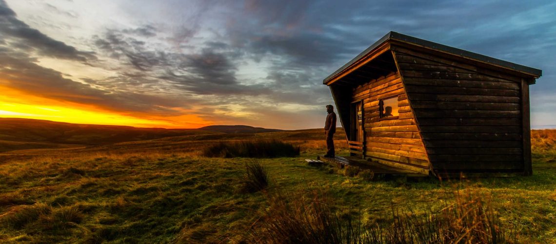 Man Standing Beside Brown House