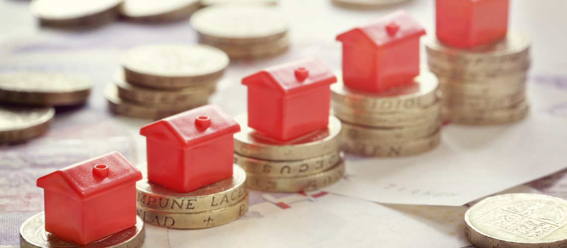 Minature houses resting on pound coin stacks concept for propert