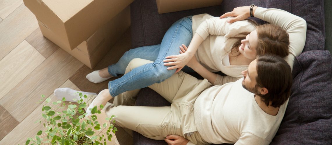 Relaxed Couple Resting On Sofa On Moving Day, Young Renters Rela